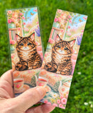 Cute cat bookmark with fluffy coat, chibi cat, floral reading nook, tea set, flowers, and matte or laminated finish options.